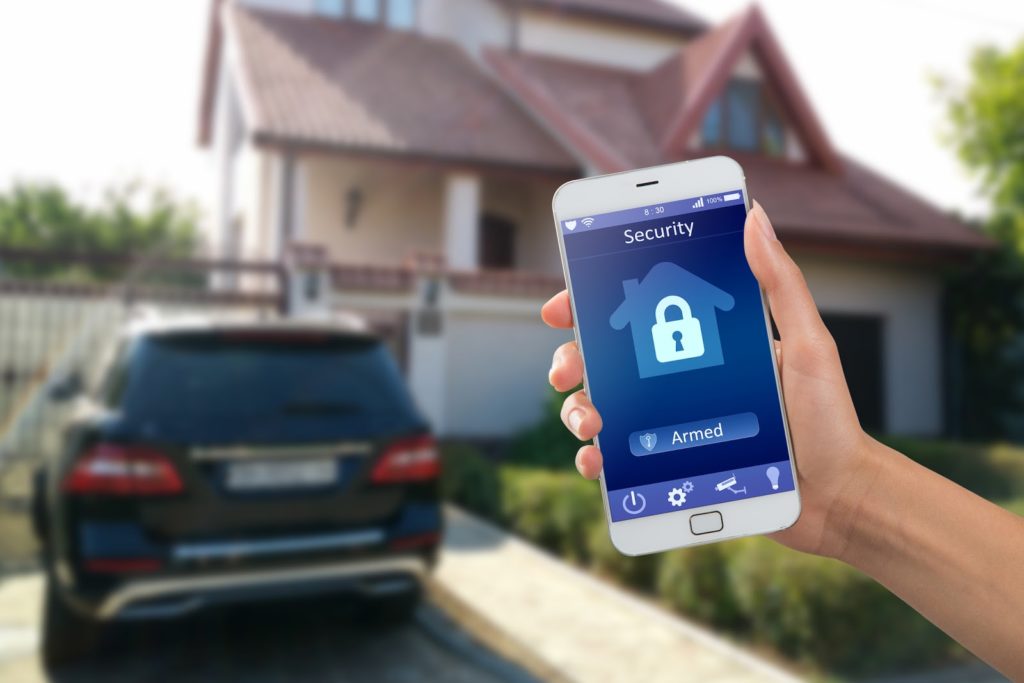 Smartphone with security app in a hand with a home in the background